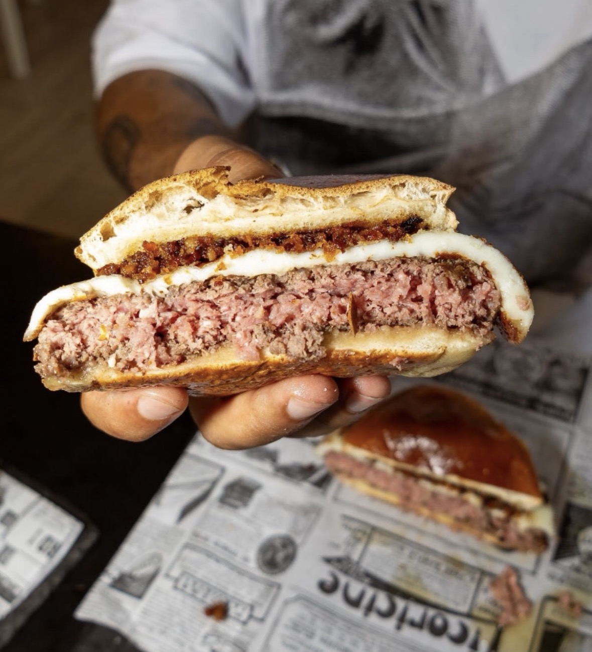 Corte de hambúrguer artesanal com queijo derretido e farofa de bacon